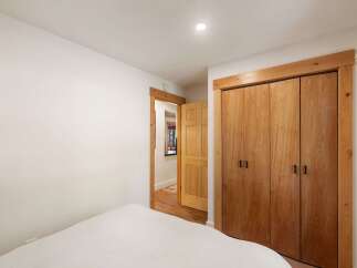 Discover this charming bedroom featuring a spacious closet with beautiful natural wood doors, offering ample storage.