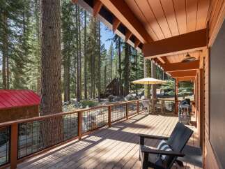 Enjoy outdoor living on this spacious wooden deck, perfect for entertaining or relaxing amidst a serene forest setting.