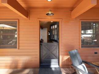 Step onto the charming porch of this cozy cabin, featuring a unique Dutch door that opens to reveal a warm interior.