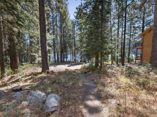 Discover your dream mountain retreat nestled amongst tall pine trees with a glimpse of a serene lake.