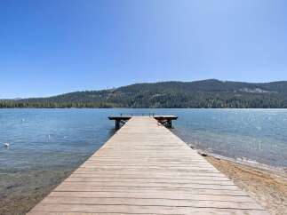 Enjoy direct lake access from this stunning property featuring a private wooden dock perfect for swimming, boating, or simply soaking in the breathtaking mountain and water views.