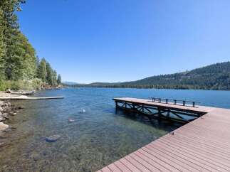 Enjoy serene lakefront living with this stunning property featuring a spacious wooden dock perfect for swimming, sunbathing, or launching your boat.