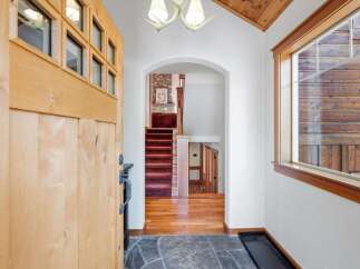 Step into a warm and inviting entryway featuring a rustic wooden door with glass panes and a stone tile floor.