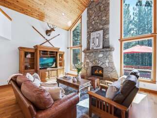 Experience rustic charm in this inviting living room, featuring a grand stone fireplace and a vaulted wood-paneled ceiling.