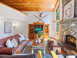 Experience rustic charm in this inviting living room, featuring a grand stone fireplace and a beautiful wooden entertainment center.