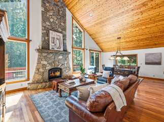 Experience rustic charm in this stunning living room, featuring a grand stone fireplace and soaring vaulted wood ceilings.