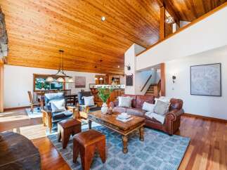 Experience rustic charm in this spacious living area featuring a soaring wood-paneled vaulted ceiling and a cozy stone fireplace.