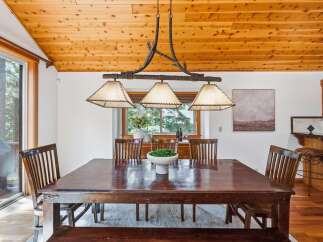 Experience rustic charm in this inviting dining room, featuring a grand wooden table perfect for gatherings and a unique chandelier overhead.