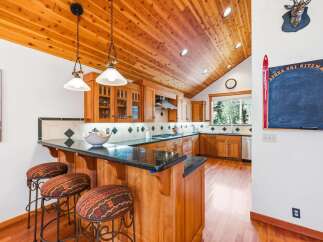 Experience rustic charm in this inviting kitchen featuring warm wood cabinetry and a vaulted cedar plank ceiling.