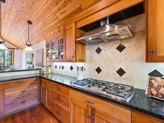 Experience the warmth of this inviting kitchen, featuring rich cherry wood cabinetry and a stunning vaulted wood-plank ceiling.