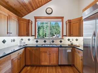 This charming kitchen boasts beautiful natural wood cabinetry and a vaulted wood-paneled ceiling, creating a warm and inviting atmosphere.