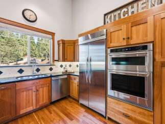 This spacious kitchen boasts beautiful cherry wood cabinetry and sleek stainless steel appliances, including a double oven and a large refrigerator.