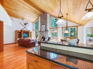 Experience rustic charm in this stunning living area, featuring a soaring wood-paneled vaulted ceiling and a magnificent stone fireplace.