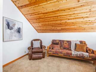 Cozy up in this charming living space featuring a plush leather armchair and a comfortable futon adorned with a rustic bear-themed throw.