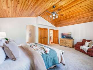 Experience ultimate comfort in this spacious bedroom, featuring a luxurious king-size bed adorned with plush pillows and a cozy throw blanket.