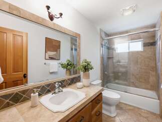 This beautifully updated bathroom features a spacious vanity with a large mirror and a modern sink, complemented by elegant tilework.