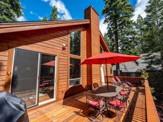 Enjoy outdoor living on this spacious wooden deck, perfect for entertaining or relaxing amidst the tall pine trees.