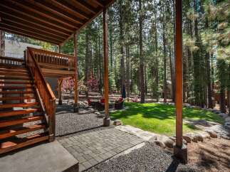 Enjoy the serene mountain lifestyle with this stunning property featuring a spacious wooden deck and outdoor seating area, perfect for entertaining or relaxing amidst the towering pine trees.
