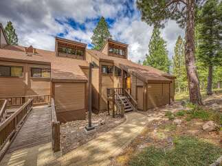 Discover this charming mountain retreat featuring a warm, wood-paneled exterior and a welcoming entrance with a wooden walkway and stairs.