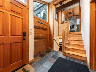 Step into this charming mountain retreat, featuring a warm and inviting entryway with a solid wood door and a convenient coat rack.