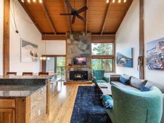 Experience the ultimate mountain retreat in this stunning living area, featuring a grand stone fireplace and vaulted wood-beamed ceilings.