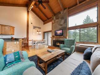 Experience cozy mountain living in this charming living room featuring a stunning stone fireplace and vaulted wood-beamed ceilings.