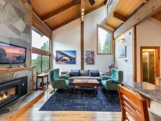 Experience rustic charm and modern comfort in this stunning living room, featuring a grand stone fireplace and soaring vaulted ceilings with exposed wooden beams.