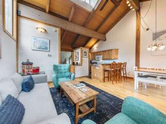 Experience rustic charm in this open-concept living space, featuring a vaulted wood-beam ceiling and a cozy fireplace.