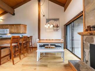 Experience rustic charm in this open-concept living space, featuring a vaulted wood-beamed ceiling and a cozy stone fireplace.