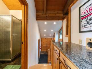 Discover a charming interior featuring a well-appointed bathroom with a glass-enclosed shower and a toilet, complemented by dark tiled flooring and a green bath mat.