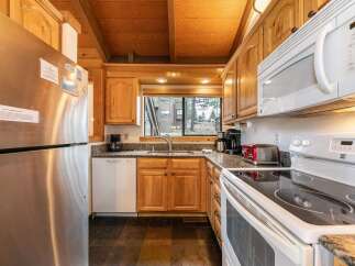 This charming kitchen features warm wooden cabinetry and a spacious stainless steel refrigerator, perfect for storing all your groceries.