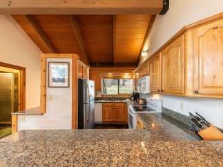 Experience rustic charm in this kitchen featuring warm wooden cabinetry and exposed beam ceilings.