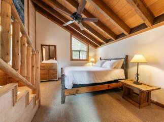 Experience rustic charm in this cozy bedroom featuring a beautiful log-style bed and a wooden ceiling fan.