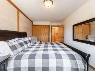 This charming bedroom features a cozy queen-size bed with a classic buffalo check comforter, perfect for a restful night's sleep.