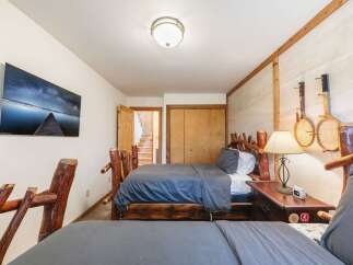 This rustic bedroom features two cozy beds with unique log-style headboards, perfect for a cabin retreat.