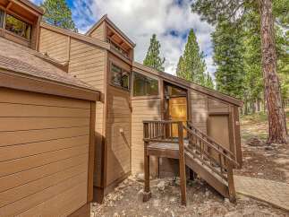 Discover this charming mountain home featuring a rustic wood exterior and a welcoming wooden front door.