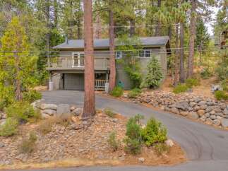Nestled amidst towering pine trees, this charming home offers a serene retreat with its natural wood siding and expansive deck perfect for enjoying the surrounding forest views.