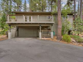 Nestled amongst tall pine trees, this charming home features a spacious upper-level deck perfect for enjoying the serene surroundings.