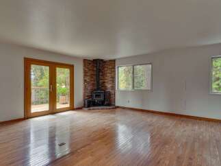 Experience cozy living in this spacious room featuring a charming brick fireplace with a wood-burning stove, perfect for gathering on cooler evenings.