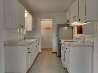 This charming kitchen features crisp white cabinetry and countertops, offering a bright and airy feel.