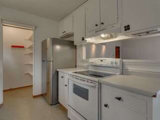 This charming kitchen features a spacious pantry with ample shelving, perfect for all your storage needs.