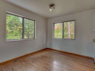 This charming room features beautiful hardwood floors and large windows that offer a serene view of the surrounding trees.