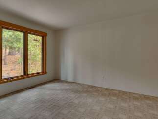 This spacious room features a large window with a wooden frame, offering picturesque views of the surrounding trees and nature.