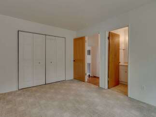 This spacious bedroom features a large, neutral-toned carpet and ample closet space with bi-fold doors.