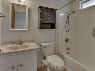 This charming bathroom features a pristine white vanity with a marble countertop and a matching sink, complemented by a decorative medicine cabinet above the toilet.