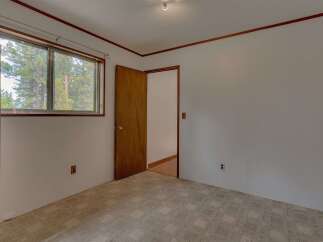 This cozy bedroom features a large window offering picturesque views of the surrounding pine trees.