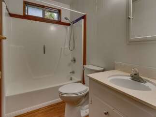 This bathroom features a clean white bathtub and shower combination, complemented by a classic white toilet.