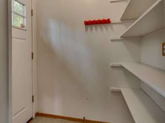 This charming entryway features a white paneled wall with a red hook rack, perfect for coats and accessories.