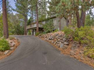 Nestled amidst tall pine trees, this charming home offers a serene retreat with a spacious deck perfect for enjoying the natural surroundings.