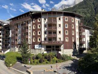 Discover this charming multi-story apartment building nestled against a backdrop of majestic mountains.